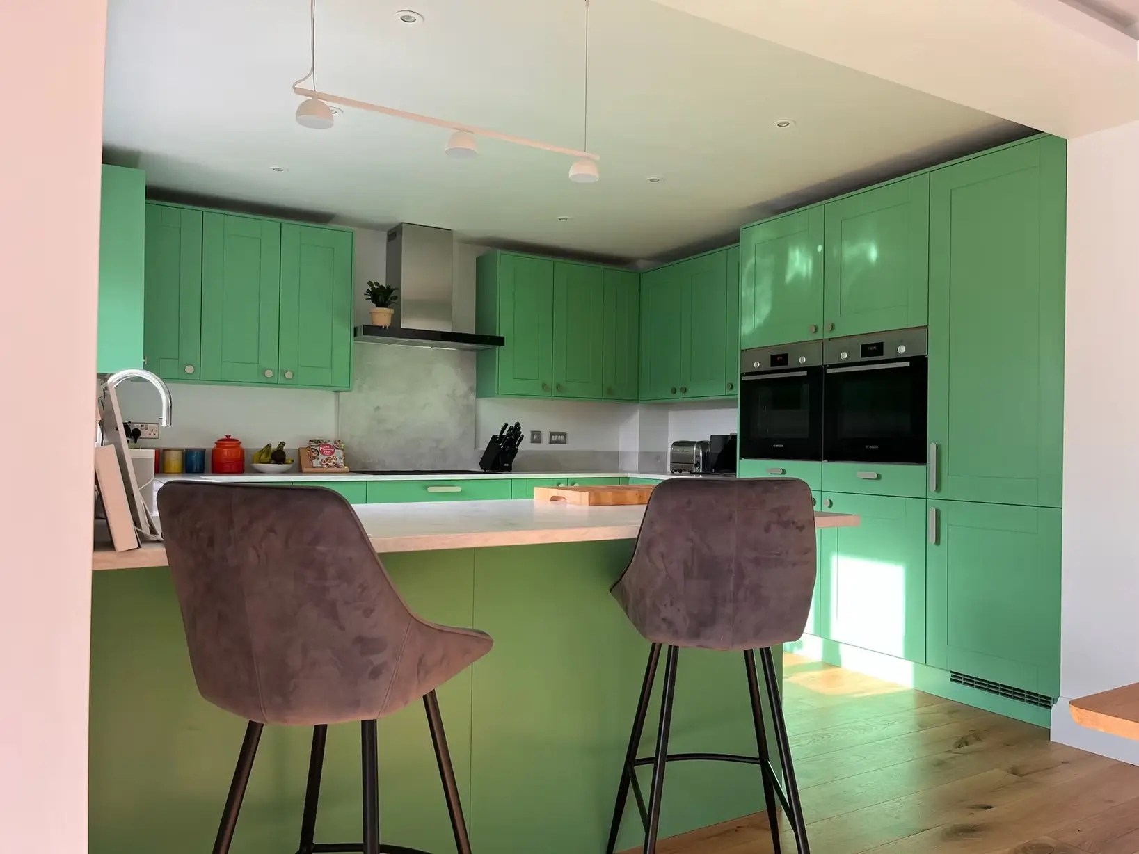 A sage green kitchen with wood countertops and a central island.